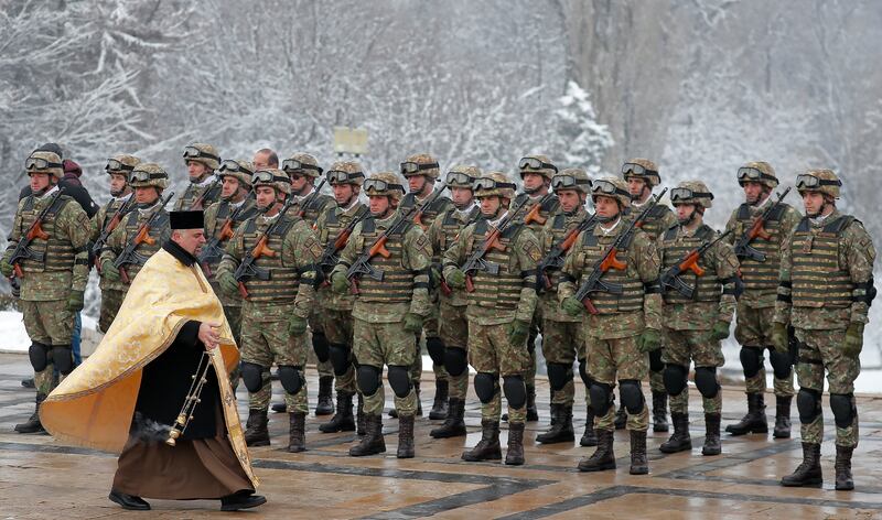 Paratroopers are blessed by a military priest during a ceremony in front of the Unknown Soldier Memorial in Bucharest to mark the 165th anniversary of the Unification of the Romanian Principalities. EPA