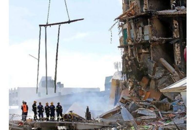 Rescuers stand at the smoking ruins of the CTV building in Christchurch, New Zealand, where 48 students and staff, including scores of Asian students, are feared buried.