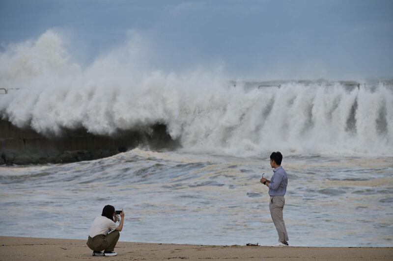 A couple take photos along a sea wall of the waves brought by Typhoon Haishen in the eastern port city of Sokcho. AFP