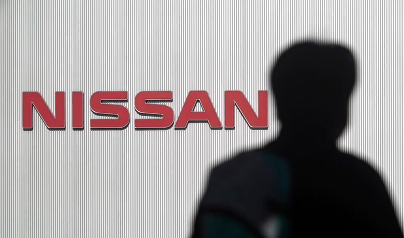 FILE- In this Nov. 21, 2018, file photo, a man walks past the logo of Nissan Motor Co. at Nissan Motor Co. Global Headquarters in Yokohama near Tokyo. Nissan is among a growing list of top-name Japanese companies whose corporate governance has been found lacking in recent years. (AP Photo/Eugene Hoshiko, File)