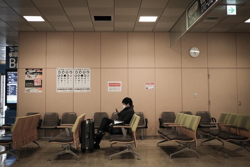 A traveler wearing a protective mask sits with his luggage in Shinjuku Expressway Bus Terminal in Tokyo, Japan. Bloomberg