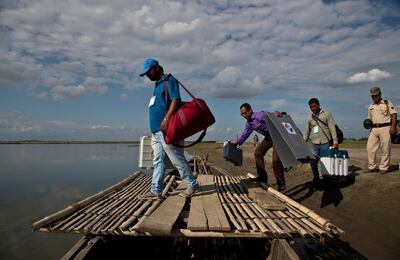 Indian election officials and paramilitary soldiers with election materials board on a country boat to cross the river Brahmaputra on the eve of first phase of general election in Majuli, Assam, India, Wednesday, April 10, 2019. Voting will take place in seven phases over six weeks beginning Thursday. Nearly 900 million people, including 15.9 million first-time voters, are eligible to cast ballots in the world's largest democratic exercise. (AP Photo/Anupam Nath)