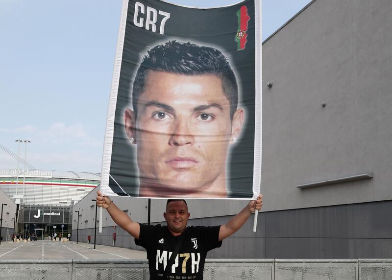 A Juventus supporter holds a banner bearing the picture of Ronaldo in front of the Juventus medical center. AFP