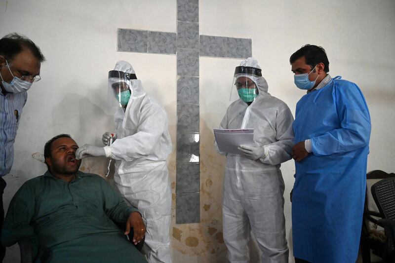 A health official (C) wearing Personal Protective Equipment (PPE) takes a swab sample in Islamabad. AFP
