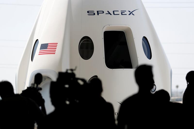 Members of the media gather around a replica of the Crew Dragon spacecraft. Reuters