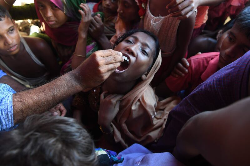 A Rohingya refugee receives an oral cholera vaccine from a Bangladeshi volunteer at the Thankhali refugee camp in Ukhia district on October 10, 2017.
The United Nations launched one of its biggest ever cholera vaccination drives in the vast refugee camps of southeast Bangladesh on October 10 amid fears of an outbreak among nearly a million Rohingya now living there. / AFP PHOTO / INDRANIL MUKHERJEE
