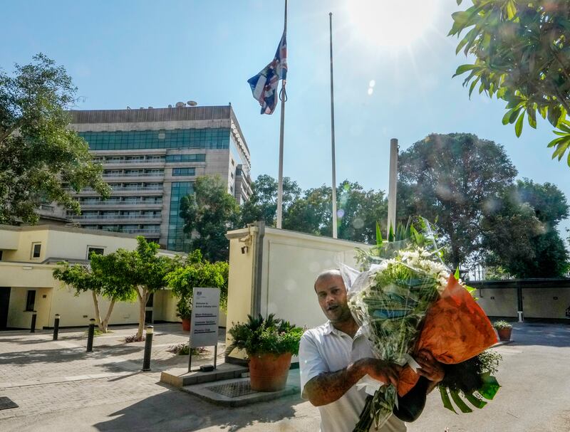 A worker carries mourners' flowers in the British Embassy in Cairo, Egypt. AP