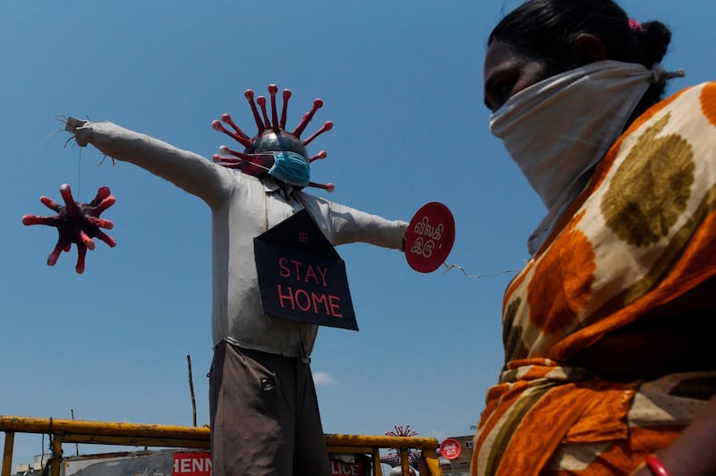 A women wearing a facemask walks past a Covid-19 awareness scarecrow placed by Chennai municipality at a market during a government-imposed nationwide lockdown as a preventive measure against the COVID-19 coronavirus, in Chennai on April 11, 2020.  / AFP / Arun SANKAR                        
