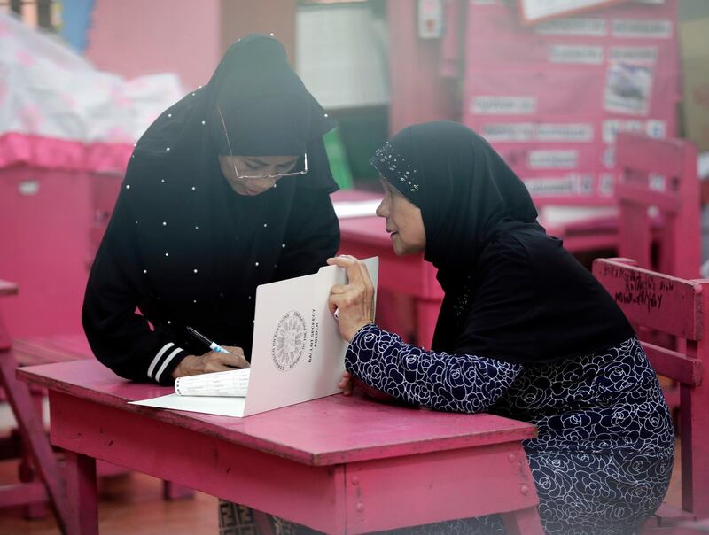 epa07566273 A Filipino Muslim elderly woman (R) is assisted by a relative to fill out her ballot at an elementary school turned into a voting precinct in Manila, Philippines, 13 May 2019. Over 61 million Filipinos are expected to cast their vote in the country's mid-term elections, wherein over 43,000 candidates are vying for some 18,000 electoral posts including seats in the Philippine Senate and House of Representatives.  EPA/FRANCIS R. MALASIG
