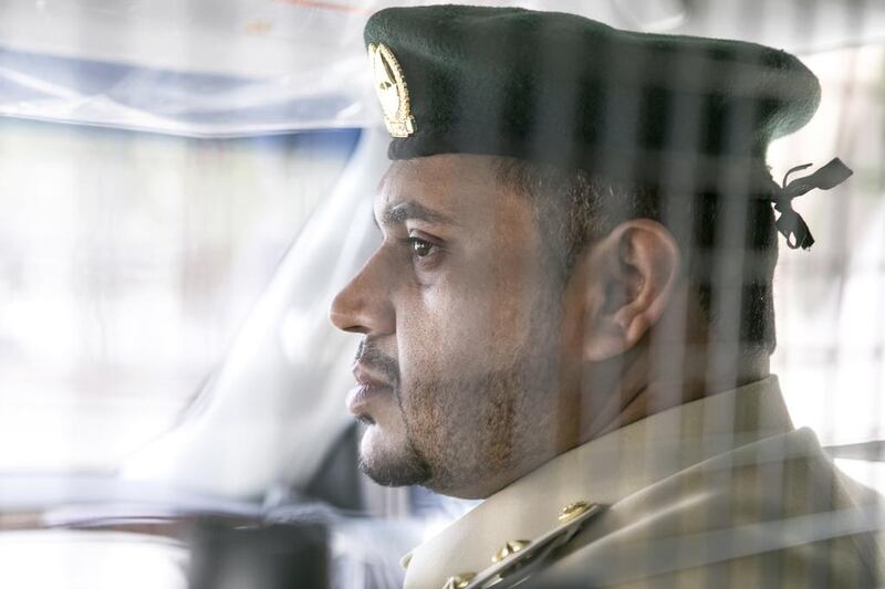 First Lieutenant Essa Ahmed sits in a patrol car.