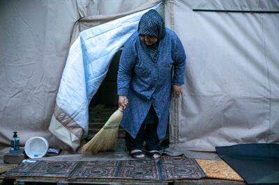 A woman sweeps the entrance to the tent in which her family are living having been displaced, in Kahramanmaras, Turkey. AP