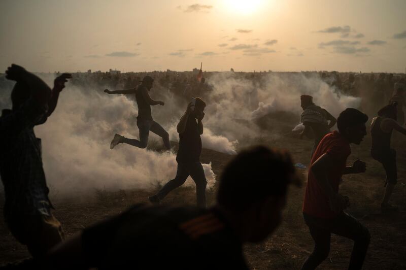 Palestinian protesters kick back teargas fired by Israeli troops during a protest at the Gaza Strip's border with Israel, east of Gaza Cit. AP Photo