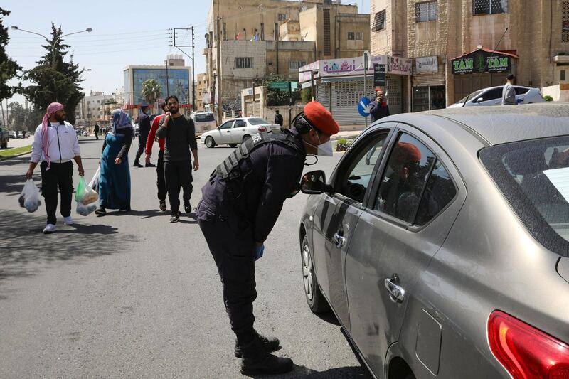 A Jordanian police officer is seen at a checkpoint as people walk in the street after Jordan announced it would allow people to go on foot to buy groceries in neighborhood shops, amid concerns over the spread of coronavirus disease (COVID-19), in Amman, Jordan March 25, 2020. REUTERS/Muhammad Hamed