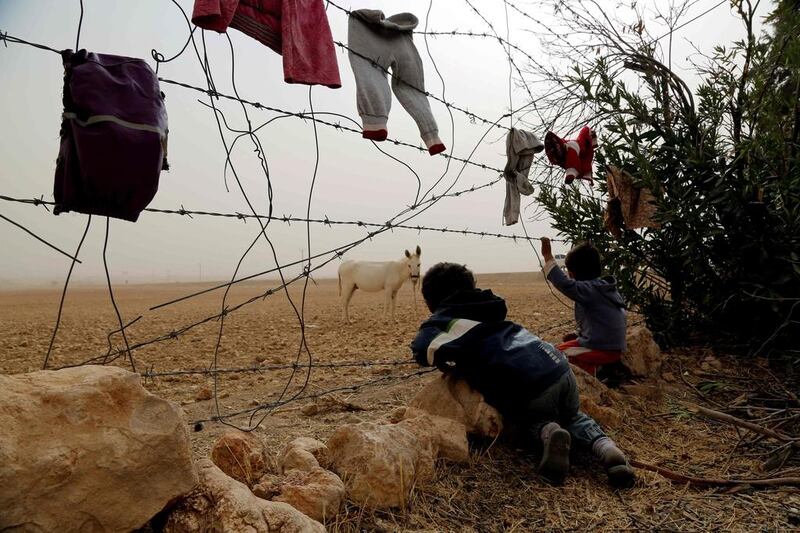 Syrian children look at a donkey from behind the fence at a temporary refugee camp in the village of Ain Issa, housing people who fled ISIL’s Syrian stronghold of Raqa, some 50 kilometres north of the group’s de facto capital on November 10, 2016. The US-backed Syrian Democratic Forces (SDF) said their advance on Raqa was being delayed by a sandstorm. Delil Souleiman / Agence France-Presse