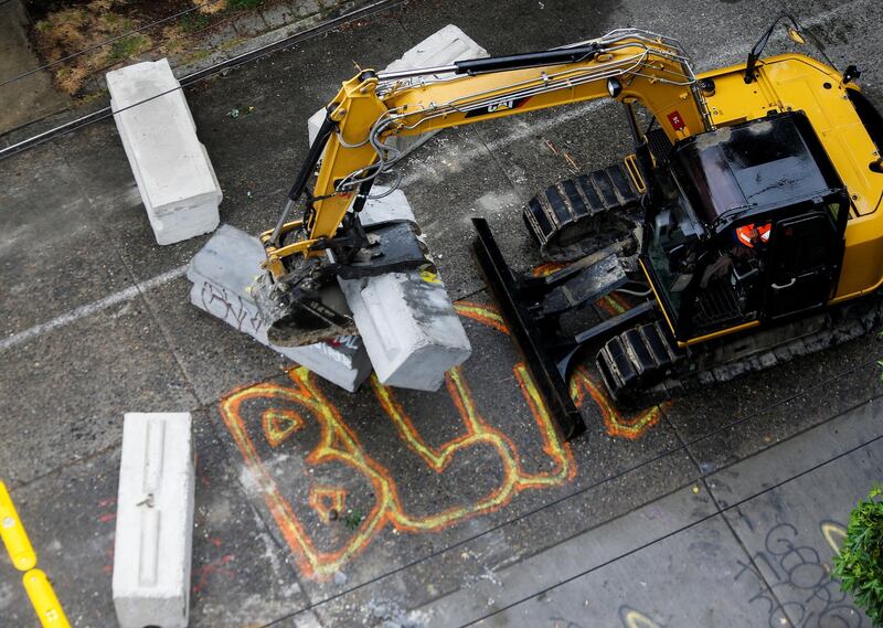 A city worker moves concrete barricades away near "BLM" graffiti as Seattle Police retake the Capitol Hill Occupied Protest (CHOP) area. Reuters