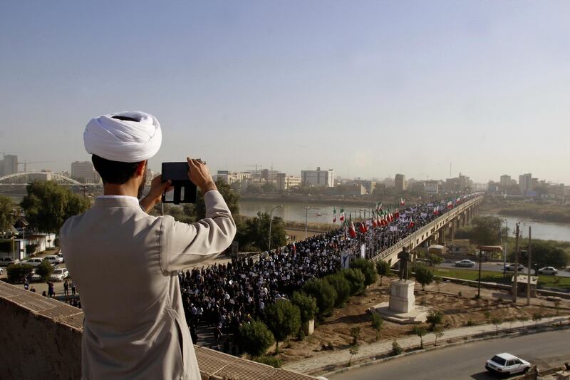 In this photo provided by the Iranian Students' News Agency, a clergyman takes a picture of a pro-government demonstration in the southwestern city of Ahvaz, Iran, Wednesday, Jan. 3, 2018. Tens of thousands of Iranians took part in pro-government demonstrations in several cities across the country on Wednesday, Iranian state media reported, a move apparently seeking to calm nerves after a week of deadly protests and unrest over the country's flagging economy. (Mohammad Ahangari/ISNA via AP)