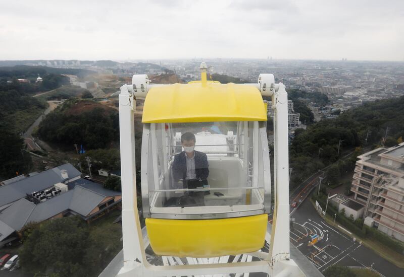 A man uses a laptop on a Ferris wheel at 'Amusement Workation' at Yomiuriland in Tokyo, Japan. The park lets people work remotely from its Ferris wheel and pool side. Reuters