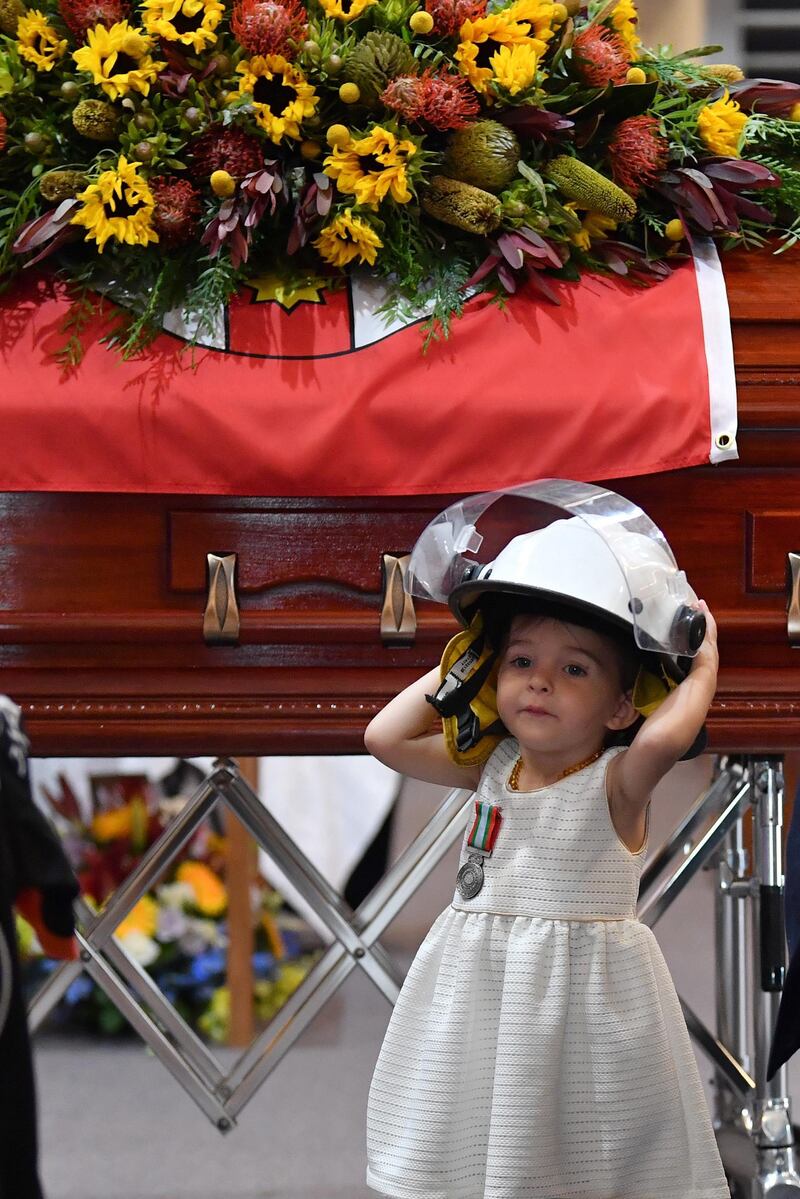 Charlotte O'Dwyer, daughter of late NSW RFS volunteer Andrew O'Dwyer, wears her father's helmet during a funeral at Our Lady of Victories Catholic Church in Horsley Park, Sydney.  EPA