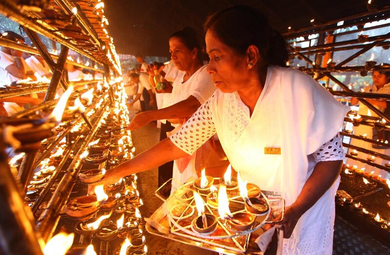 Sri Lankan Buddhist Devotees light lamps at a temple on full moon day in Kelaniya, Colombo, Sri Lanka.   EPA