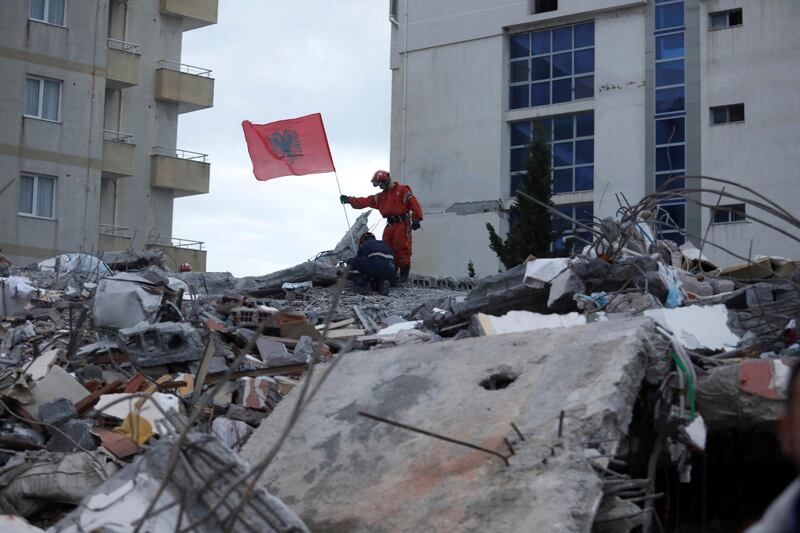 Emergency personnel place an Albanian flag on top of rubble during a search for survivors. Reuters