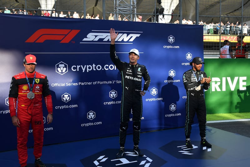 George Russell on the podium alongside second-placed Ferrari driver Carlos Sainz Jr and third-placed Mercedes driver Lewis Hamilton. AFP