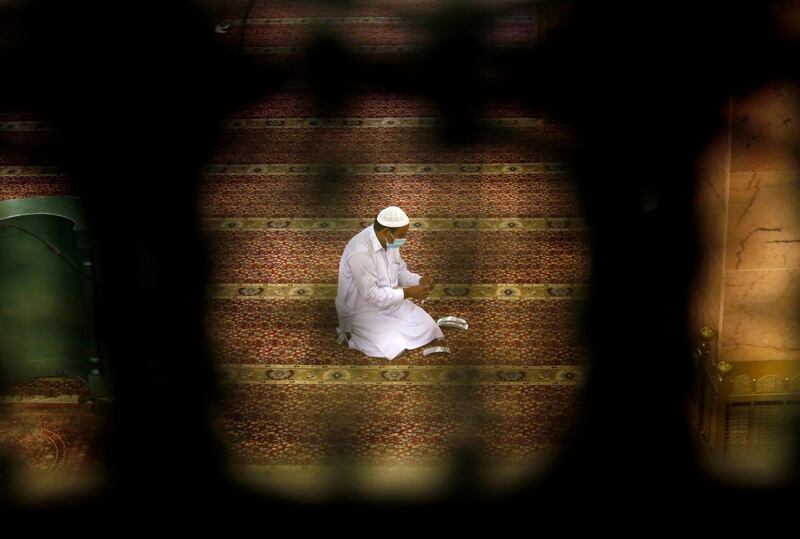 A worker is seen through a window as he places markers to ensure social distancing at Al Mirabi Mosque in Jeddah, Saudi Arabia. AP Photo