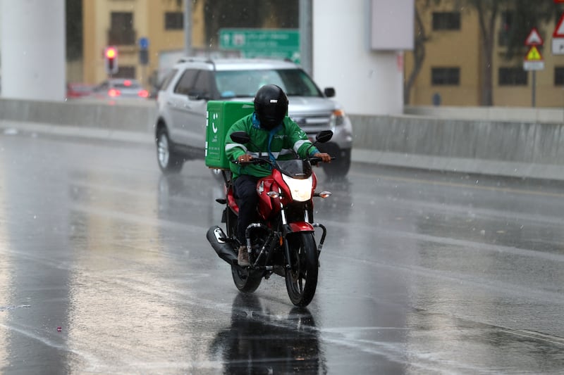 A delivery motorcyclist negotiates the rain-slicked roads of Dubai. Police warned road users to be extra vigilant in the wet conditions
