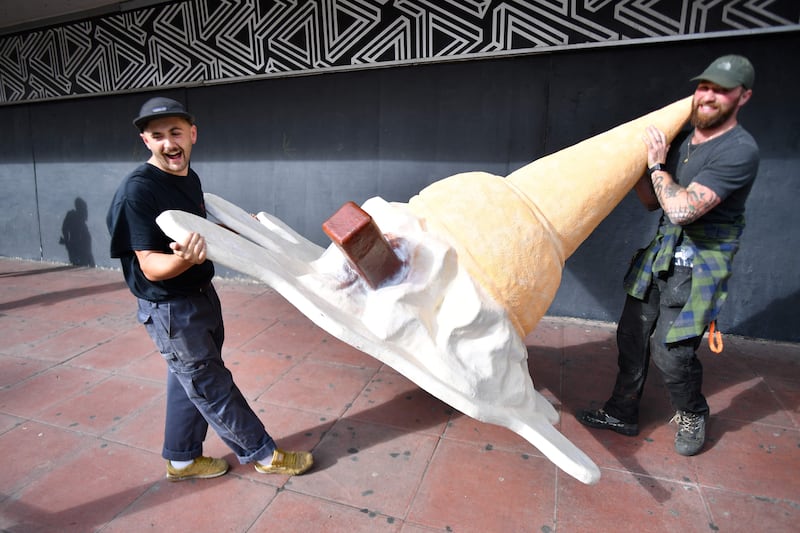 Visual artists carry an oversized sculpture of an ice cream outside the conference. AFP