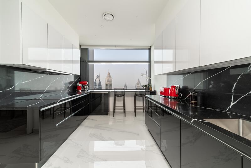 The kitchen is finished with sleek black and white fittings and bold red appliances