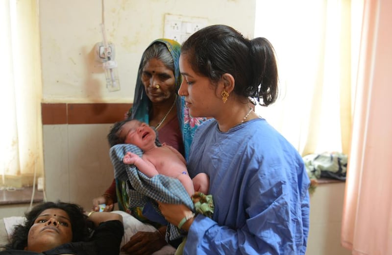 An Indian nurse holds a newborn baby girl as she explains the importance of breast feeding to her mother and grandmother at a hospital in Shivpuri, central Madhya Pradesh.  Roberto Schmidt / AFP

