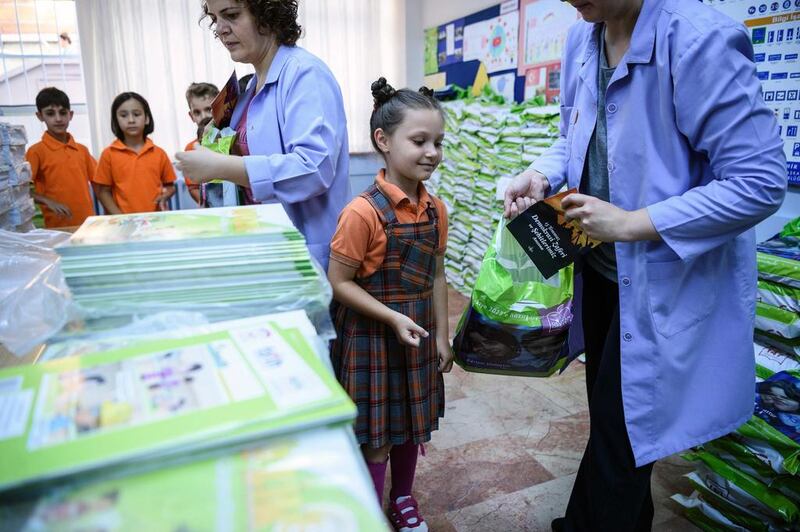 A teacher gives a school child a booklet entitled 'In memory of July 15, the Martyrs and the Victory of Democracy' as she collects her school books during the first day back at school on September 19, 2016 in Istanbul. AFP

