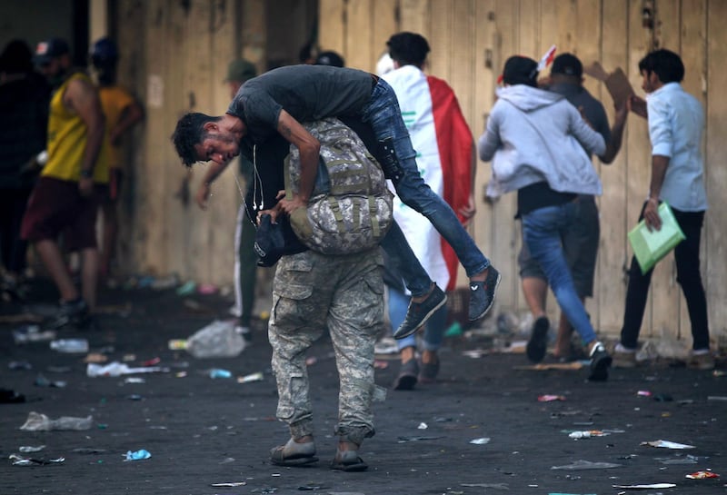 An Iraqi protester carry away a wounded comrade amid clashes with security forces at Baghdad's Khallani square during ongoing anti-government demonstrations. AFP