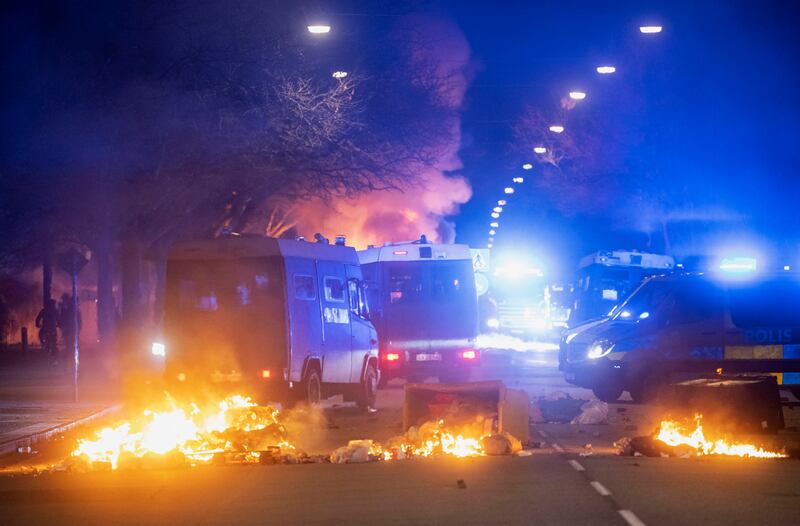 Police vehicles next to a burning barricade in Malmo. AP