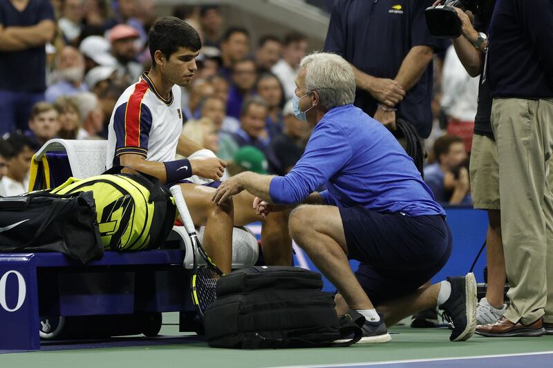Carlos Alcaraz of Spain talks with a trainer during his quarter-finals match against Felix Auger-Aliassime of Canada before retiring hurt. Getty