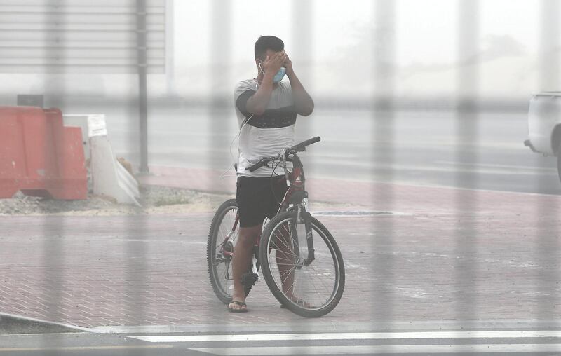 DUBAI, UNITED ARAB EMIRATES , July 21 – 2020 :- A cyclist covering his eyes during the sandstorm in Discovery Gardens area in Dubai.  (Pawan Singh / The National) For News/Standalone/Online/Stock