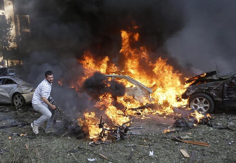 A Lebanese man tries to pull a  body out of a burned car. Hussein Malla / AP Photo