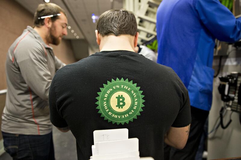 A trader wears a Bitcoin shirt while working in the S&P 500 options pit at Cboe Global Markets Inc. in Chicago, Illinois, U.S., on Friday, Dec. 29, 2017. U.S. stocks slipped in thin trading on the final market day of 2017, while the dollars slump continued as the euro headed for its best annual performance in 14 years. The S&P 500 Index turned lower in trading 45 percent below the 30-day average, leaving its gain this year just under 20 percent, the most since 2013. Photographer: Daniel Acker/Bloomberg