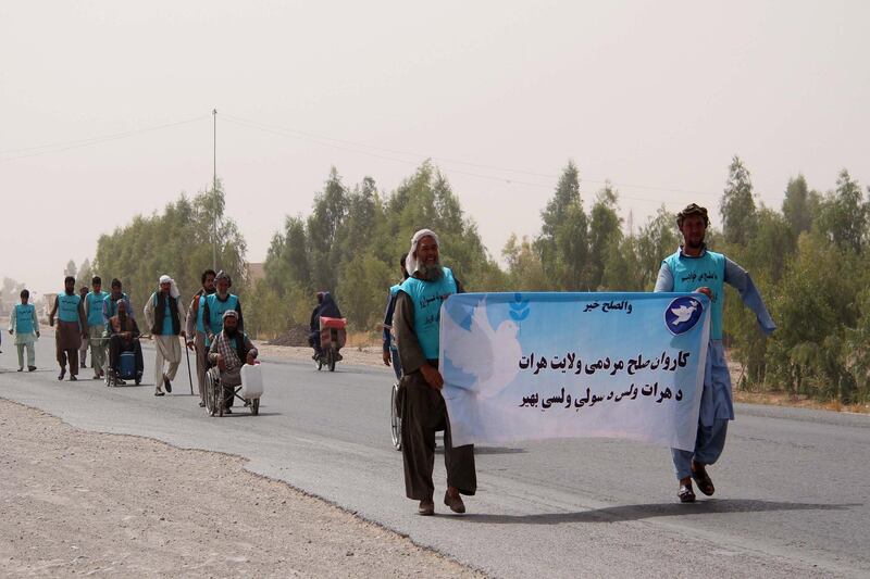 Afghan people, some in wheelchairs, hold pamphlets and banners reading in Dari 'Peace March' as they reach Helmand province on a journey by foot from Herat province to Kabul. EPA