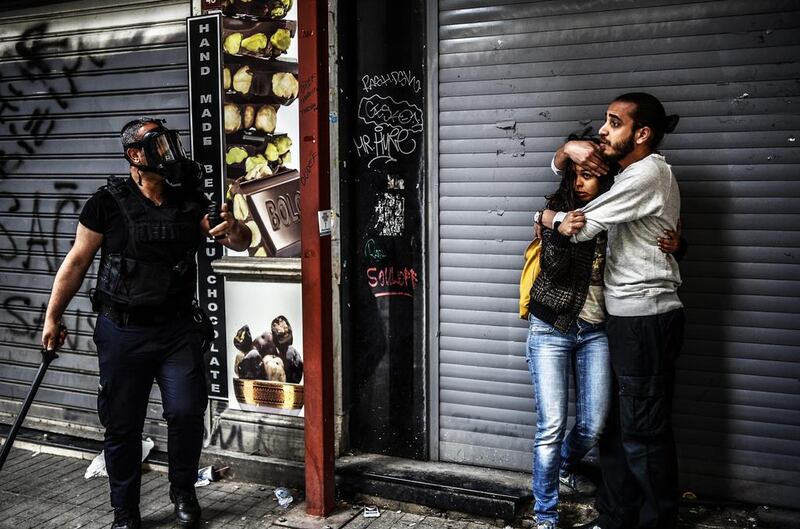 A man protects a woman as they face a police officer dispersing protesters gathering on the central Istoklal Avenue near Taksim square in Istanbul on Saturday. Bulent Kilic / AFP  