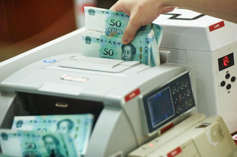 (FILES) This file photo taken on August 30, 2019 shows a Chinese bank employee counting new 50-yuan notes with a money counting machine at a bank counter in Hangzhou in China's eastern Zhejiang province, as the People’s Bank of China issues the newest 2019 edition of the fifth series of the yuan notes. Chinese police have seized counterfeit notes with a face value of 422 million yuan (59 million USD) in the largest haul since the 1949 founding of the People's Republic of China. - China OUT
 / AFP / STR
