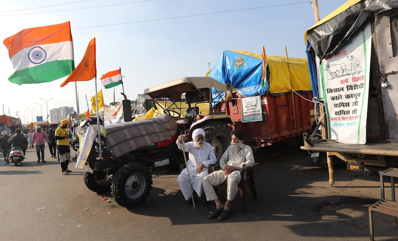 epa08991369 Indian farmers sit next to their tractors during a protest at the Delhi Ghazipur Border near New Delhi, India, 06 February 2021. Farmers announced nationwide 'Chakka Jam' or road blockade after Thousands of farmers gathered and tried to cross the sealed New Delhi border points to hold protests against the government's new agricultural laws and to demand for repealing the laws. Farmers have been stopped by the police at the various points outside the Delhi border, which are connected with neighbouring states of Haryana and Uttar Pradesh, and since then farmers have been holding sit-in protests there.  EPA/RAJAT GUPTA