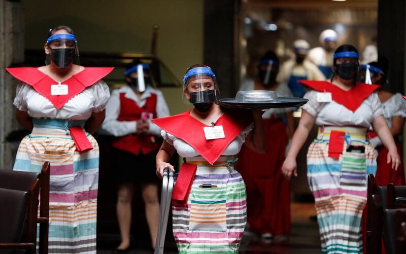 A waitress wearing a mask and face shield to curb the spread of the coronavirus brings order for a patron at the "Sanborns of the Azulejos" restaurant in Mexico City. AP Photo