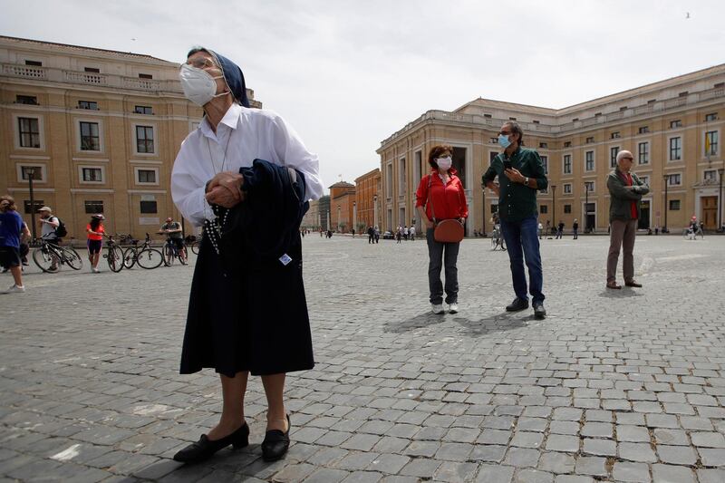 A nun wearing a face mask looks up at the window of Pope Francis' studio overlooking St Peter's square as he appears to give his blessing after the Angelus prayer, at the Vatican. AP Photo
