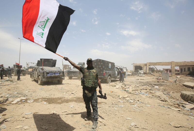 An Iraqi federal police member waves his country's national flag in celebration in the Old City of Mosul on July 8, 2017, as their part of the battle has been declared accomplished, while other forces continue to fight Islamic State (IS) jihadists in the city. / AFP PHOTO / AHMAD AL-RUBAYE