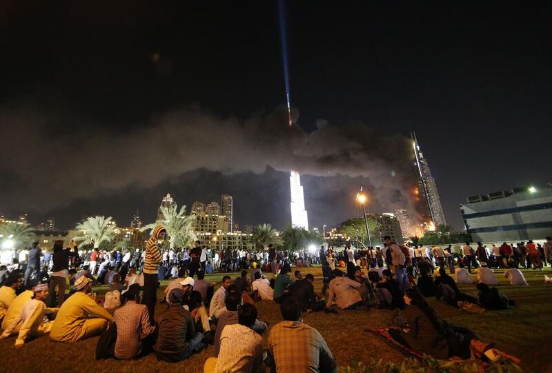People watch the Address Downtown hotel burning after huge fire ripped through the luxury hotel near the world’s tallest tower, in Dubai. People were gathering to watch New Year’s Eve celebrations when the hotel caught on fire without causing casualties, according to authorities. Karim Sahib / AFP Photo