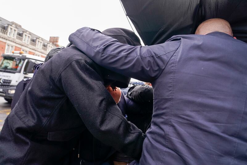 Kurt Zouma is hidden from photographers underneath umbrellas by security men as he arrives in court. PA