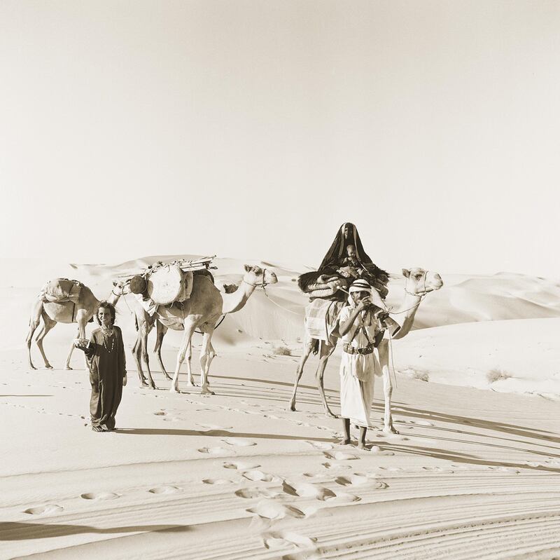 a caravan of camels and bedouin families in Asab dating to 1960 where a mother is seen on top of a camel with her child in her lap partially hidden in a â€˜bshtâ€™ cloak like abaya.

Courtesy National Center for Documentation and Research.