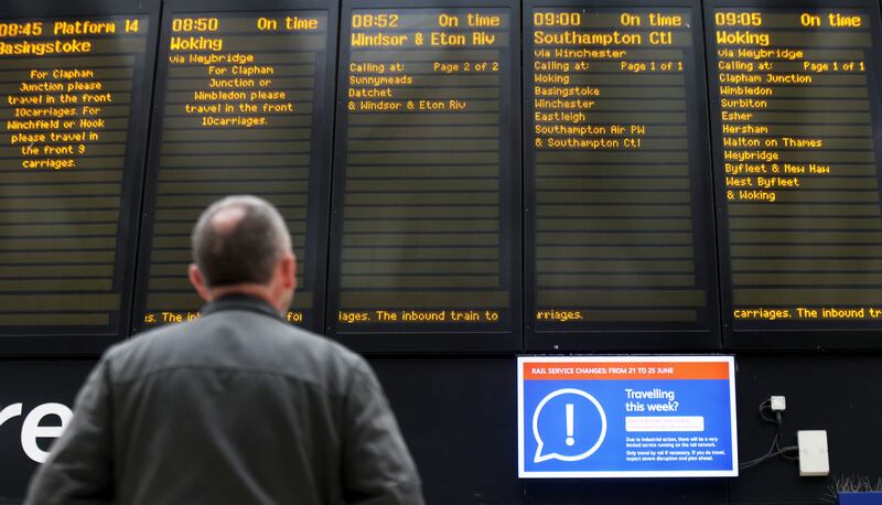 A passenger looks at the departures board at Waterloo station in London. PA