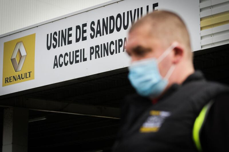 A worker of the Renault factory of Sandouville, near Le Havre, northwestern France, wears a protective facemask as he stands in front of the entrance of the the plant, on May 22, 2020 on the reopening day, as France eases lockdown measures taken to curb the spread of the COVID-19 (the novel coronavirus)  The factory of French car manufacturer Renault reopened in Sandouville (Seine-Maritime) reopened on the night between May 21 and May 22, 2020, two weeks after being condemned for sanitary measures deemed insufficient to fight against the spread of the Covid-19. / AFP / Lou BENOIST
