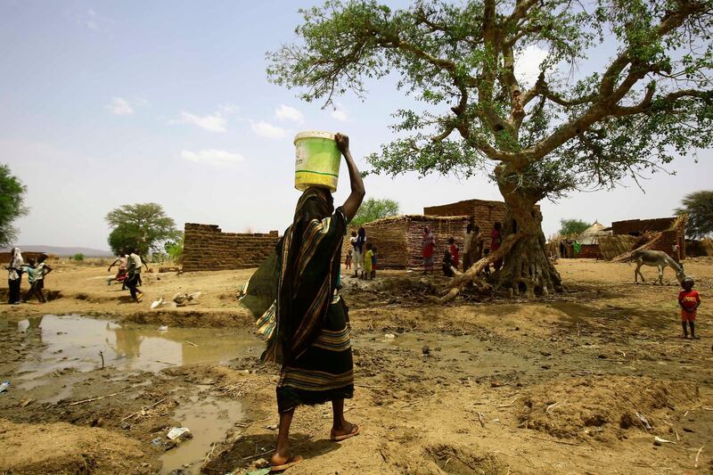 A displaced Sudanese woman walks carrying a bucket of water at a camp for Internally Displaced Persons (IDP) near Kadugli, the capital of Sudan's South Kordofan state, during a United Nations humanitarian visit on May 13, 2018. (Photo by ASHRAF SHAZLY / AFP)